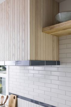 a kitchen with wooden cabinets and white tile backsplash, wood shelf above the stove