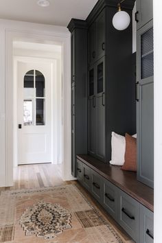 an entryway with built in cabinets and a rug on the floor next to it