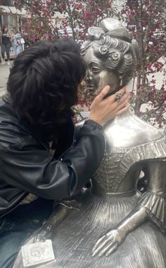 a woman sitting on top of a metal statue