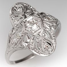 This lovely circa 1910s diamond ring features a pierced design with engraved details and bordered with milgrain edging. The ring is centered with one (1) old European cut diamond bead set into a hexagonal shaped setting. The gallery is also accented with ten (10), bead set, round single cut diamonds. The ring measures 20.2mm at the top, rises 5.8mm above the finger, tapering to 1.4mm wide and 0.9mm thick at the base of the shank. "1916" is engraved on the inside shank. It is currently a size 9.7 European Cut Diamonds, Diamond Ring, Platinum, Diamond Cuts, Jewelry Rings, Beads, 10 Things