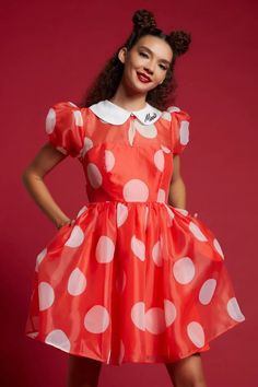 a woman in an orange dress with white polka dots on it and her hands on her hips