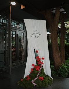 a white drape with red flowers on it in front of a building