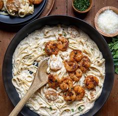 pasta with shrimp and parmesan cheese in a skillet on a wooden table