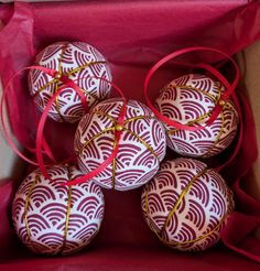 six red and white ornaments in a box with ribbon around the top, on display