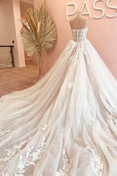 a white wedding dress on display in front of a pink wall with the words pass