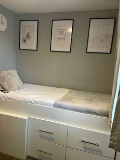 a bedroom with a bed, dresser and two clocks hanging on the wall above it