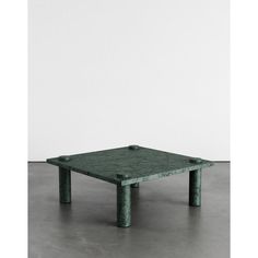 a square green table sitting on top of a cement floor