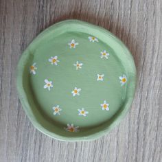 a green plate with daisies painted on it