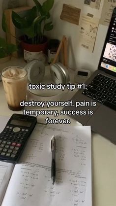 a laptop computer sitting on top of a desk next to a pen and calculator