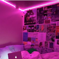 a laptop computer sitting on top of a bed in a room filled with pink walls