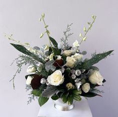 a vase filled with white flowers and greenery