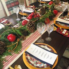 the table is set for christmas dinner with pine cones and apples