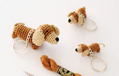 crocheted dog keychains and scissors on a white surface with one bead in the shape of a dachshune