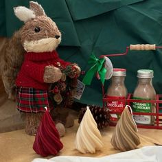 a stuffed animal wearing a sweater and scarf next to other christmas decorations on a table