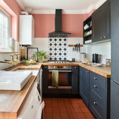 a kitchen with pink walls and black cabinets, white appliances and wooden counter tops is shown