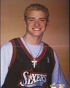 a young man wearing a basketball jersey and smiling for the camera with a necklace on his neck