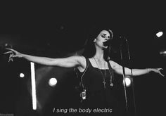 a woman standing in front of a microphone with her arms spread out and the words, i sing the body electric