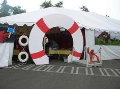 a large white tent with red and white decorations on it's sides, sitting in a parking lot