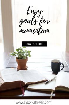 an open book, coffee cup and plant on a table with the words easy goals for momentum goal setting