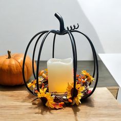 a candle sits in a decorative pumpkin - shaped container on a table with fall leaves