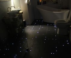 a bathroom with blue lights on the floor and a tub in the corner next to it