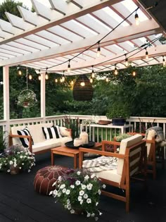 an outdoor patio with white furniture and string lights hanging from the pergolated roof