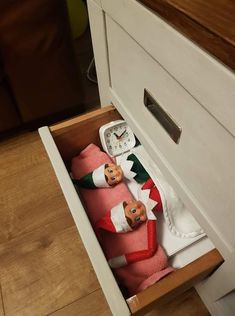 the elf is hiding in the drawer with his pink blanket and matching red sockies