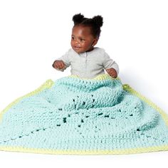 a baby sitting on top of a crocheted blanket