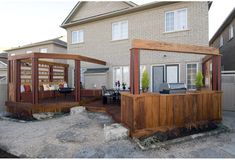 an outdoor bar with built in seating and grill area next to a home's back yard