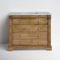 a bathroom vanity with marble top and wooden drawers on the bottom, against a white wall