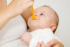 a woman feeding a baby with a spoon