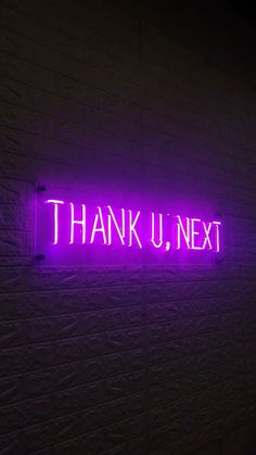 a purple neon sign that says thank u next on a white brick wall in the dark