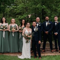 a group of people standing next to each other in front of some trees and grass