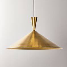 a gold colored metal light hanging from a black cord on a white wall in an empty room