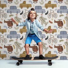 a young boy riding on top of a skateboard in front of a wallpaper