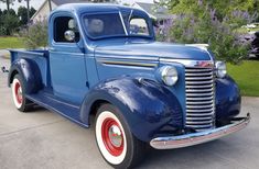 an old blue truck is parked on the driveway