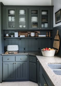 a kitchen with gray cabinets and marble counter tops