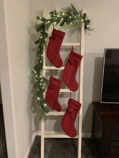 christmas stockings hanging on a ladder in front of a tv