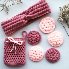 several crocheted items are laid out on a white surface with flowers in the background