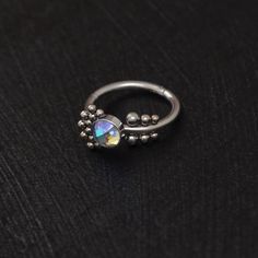 a silver ring with an opal stone in the middle on a black table top