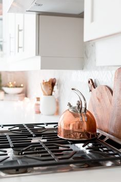 a copper pot sitting on top of a gas stove next to a wooden cutting board