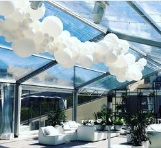 an outdoor dining area with tables, chairs and white balloons hanging from the ceiling above