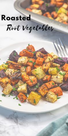 roasted root vegetables on a white plate with a fork next to it and another dish in the background