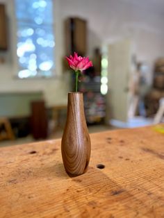 a wooden vase with a pink flower in it