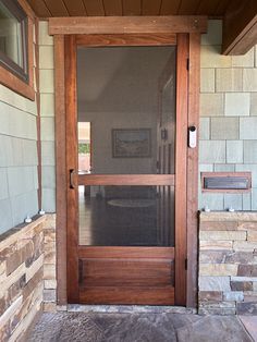 a wooden door on the side of a stone building with glass and wood trimming