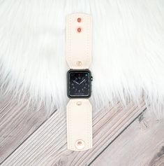 an apple watch sitting on top of a white fur covered floor