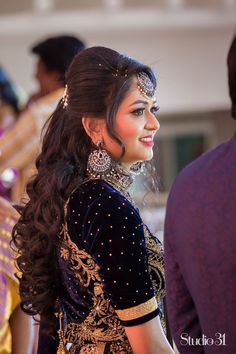 a woman with long hair wearing a black and gold outfit, standing in front of other people