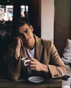 a man sitting at a table with a coffee cup and saucer in front of him