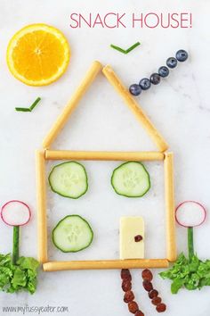 an orange, cucumber and blueberry snack house made out of popsicle sticks