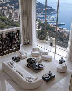 a living room filled with white furniture next to a large window covered in windows overlooking the ocean